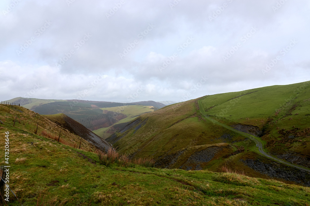 Fototapeta premium Beautiful day in Welsh mountains with a twisty road. United Kingdom, Wales in late winter.