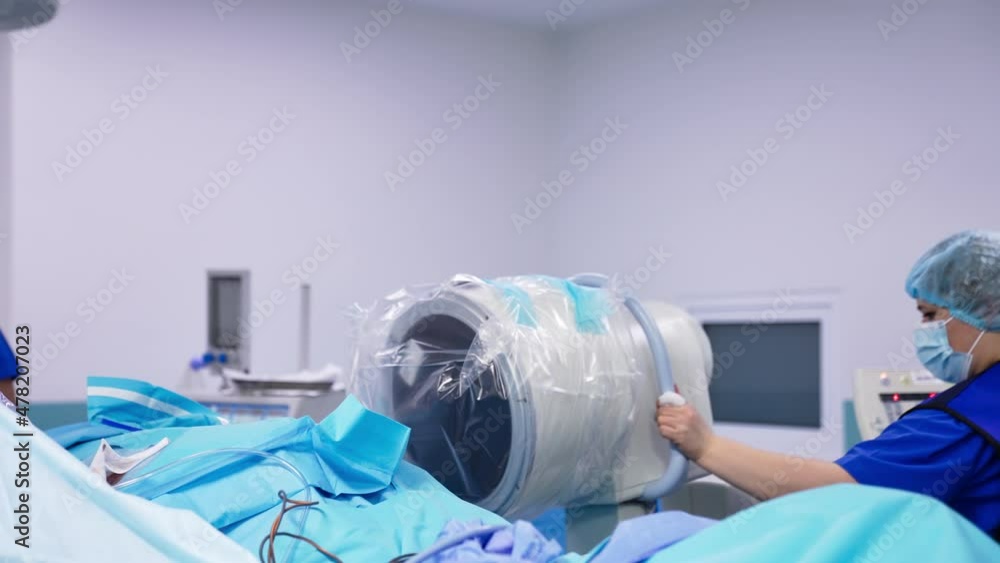 Applying innovative apparatus in surgery room. Female assistant places medical device into necessary position. Health care concept. Applying innovative apparatus in surgery room. Female assistant places medical device into necessary position. Health care concept.