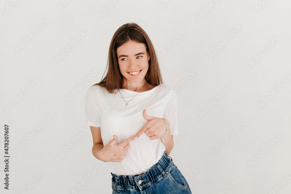 Pretty she woman in white t-shirt and jeans, thinking about her crush, being happy, touching her index fingers. Studio shot of good-looking beautiful woman on white background Pretty she woman in white t-shirt and jeans, thinking about her crush, being happy, touching her index fingers. Studio shot of good-looking beautiful woman on white background