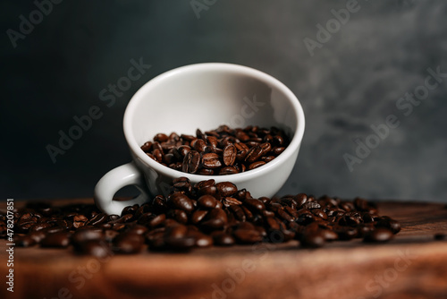 Coffee beans in a white tilted cup on a wooden table