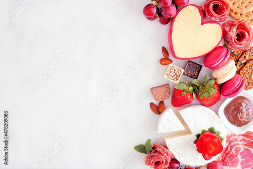 Valentine's Day theme charcuterie side border. Overhead view against a white marble background. Copy space.
