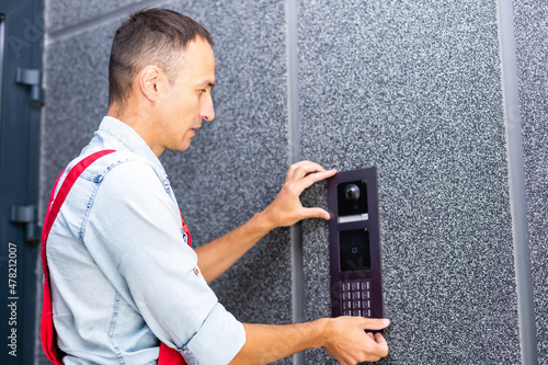 Foto handsome young electrician repairing intercom