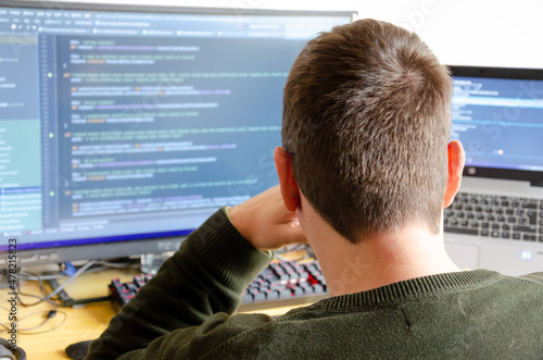 a man working on computer monitor seen from back