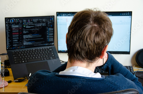 a man working on computer monitor seen from back