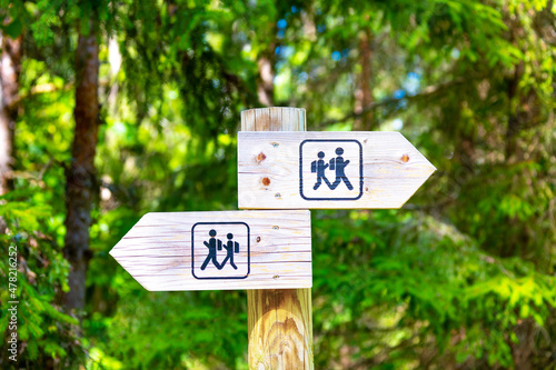 Sign of the tourist trail in the forest. Wooden sign shows tourists the directions of the trail