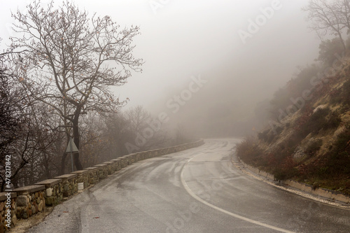 Rural road in the mountains in winter (Epirus region, Greece) on a cloudy, foggy day