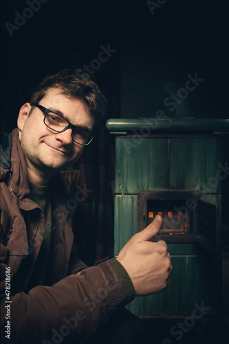Adult man in winter time drowning in the tiled stove
