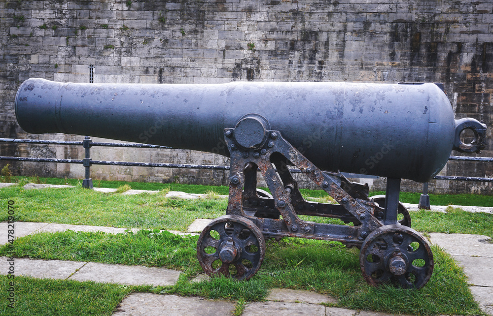 old cannon in the fortress.  Long range weapon on wheeled base next to stone wall of castle. 