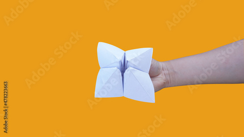 Hand holding fortune telling paper isolated on a orange background with clipping path