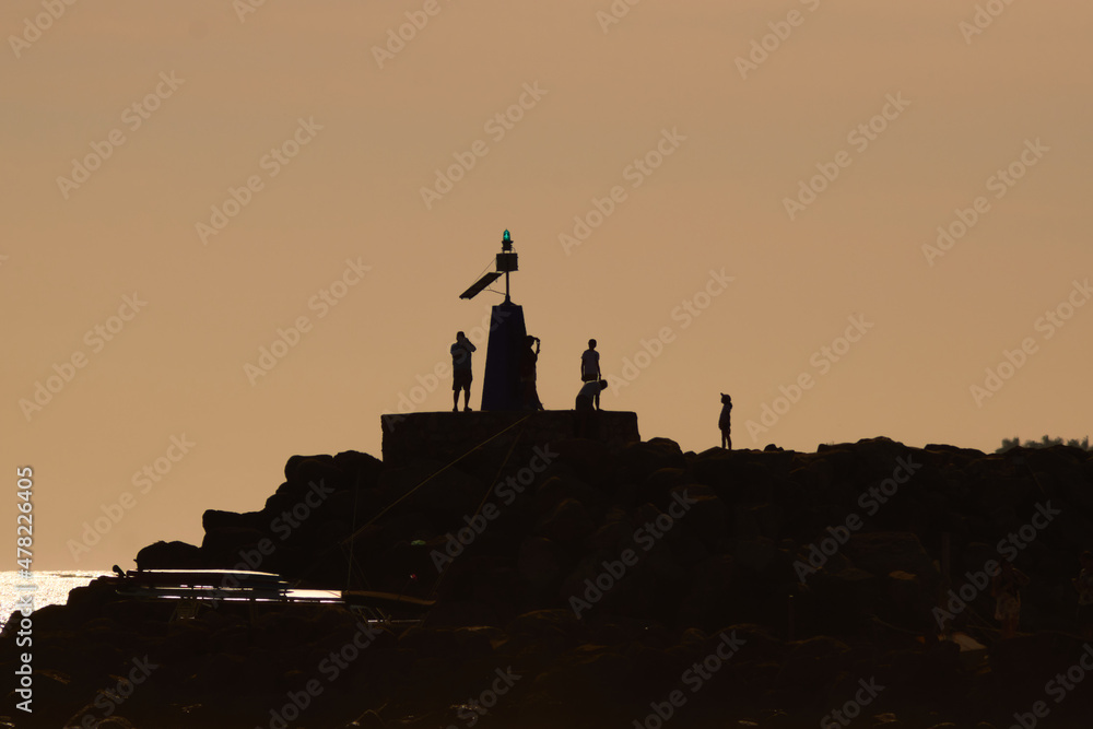 Silhouettes of people on the pier during sunset.