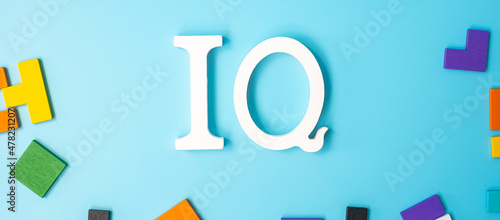 IQ text with colorful wood puzzle pieces, geometric shape block on blue background. Concept of intelligence quotient and logic thinking photo