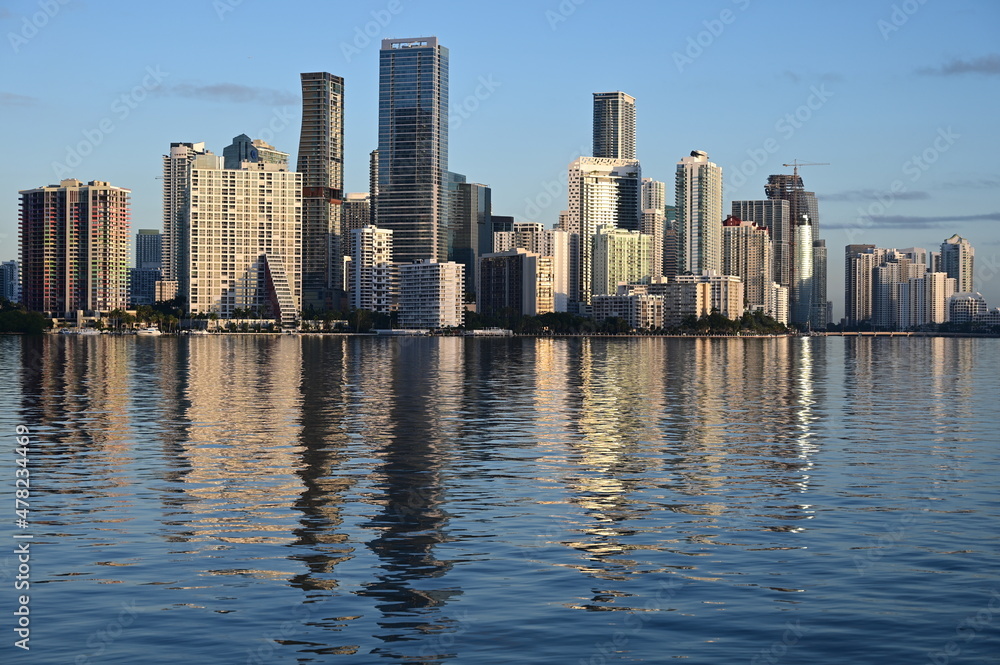 Naklejka premium City of Miami skyline reflected on tranquil water of Bisvcayne Bay in early morning light on calm clear winter day.