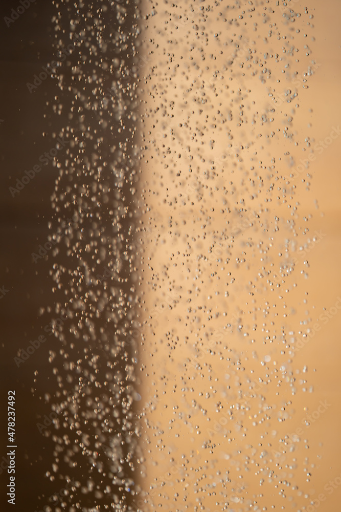 Abstract backgrond dropped water stop motion and dripping to the ground from Shower on blur orange brown background at outdoor light. Abstract backgrond dropped water stop motion and dripping to the ground from Shower on blur orange brown background at outdoor light.