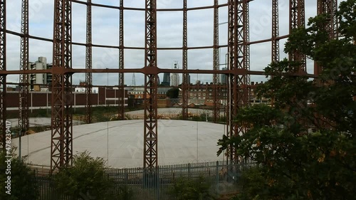 Drone footage of Victorian gas holder in Bethnal Green with London city skyline in background on cloudy day. photo