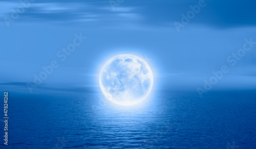 A full moon floating calmy over the sea  Elements of this image furnished by NASA 