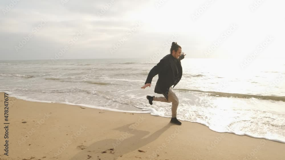 Attractive brunette man running on the wild autumn beach at sunset Attractive brunette man running on the wild autumn beach at sunset