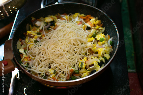 Close up Asian stir fried egg noodles with soy sauce in wok pan, high angle view