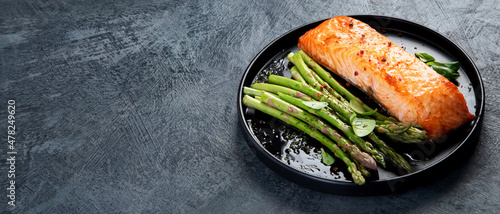 Baked salmon with asparagus on gray background. photo