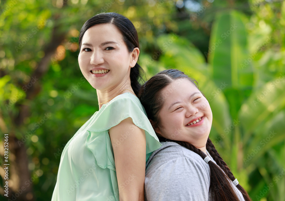 Portrait shot of Asian mother and young chubby down syndrome autistic autism little cute girl with braid pigtail hairstyle stand hugging cuddling embracing together with love smiling look at camera Portrait shot of Asian mother and young chubby down syndrome autistic autism little cute girl with braid pigtail hairstyle stand hugging cuddling embracing together with love smiling look at camera