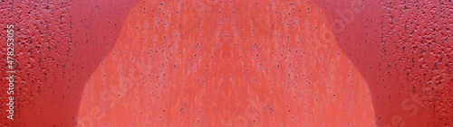 乾いた部分と濡れた部分がある赤い鉄板の表面のテクスチャー。横に長いパノラマの背景素材。