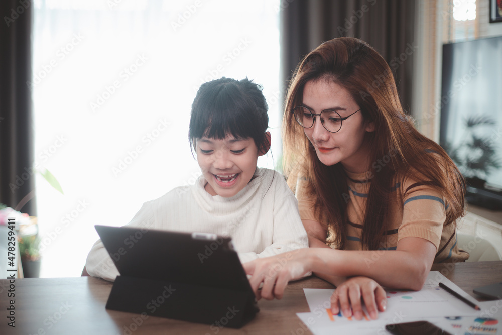 Mother's Day.Little girl looking at laptop computer with her mom.Concept family happy. stay home Mother's Day.Little girl looking at laptop computer with her mom.Concept family happy. stay home