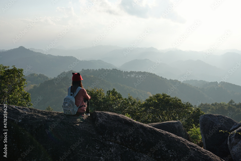 Fototapeta premium Female tourist sits looking at the beautiful mountains view.