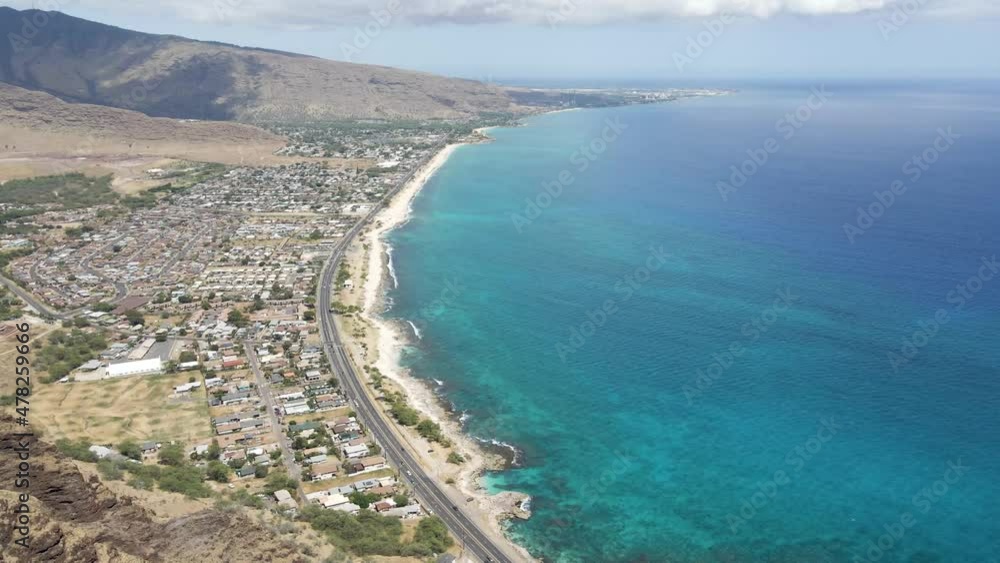 Highway with mountains and city next to tropical ocean water on coast of tropical island Highway with mountains and city next to tropical ocean water on coast of tropical island