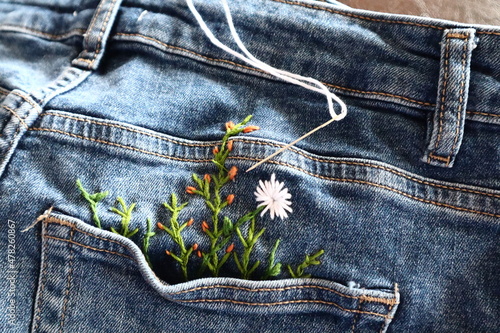 Creative DIY project, hand embroidery at home on jeans, creative hobby, clothes recycle, floral embroidery design, colorful threads, embroidery needle photo