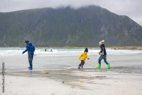 Cute child, running on norwegian white sand beach in the summer, Norway