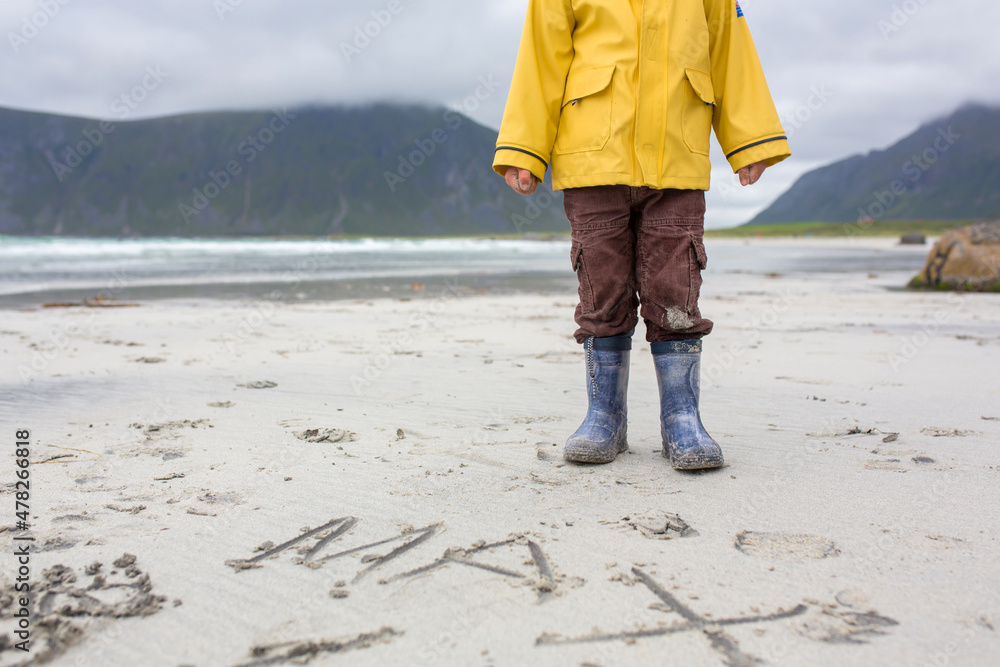 Cute child, running on norwegian white sand beach in the summer, Norway