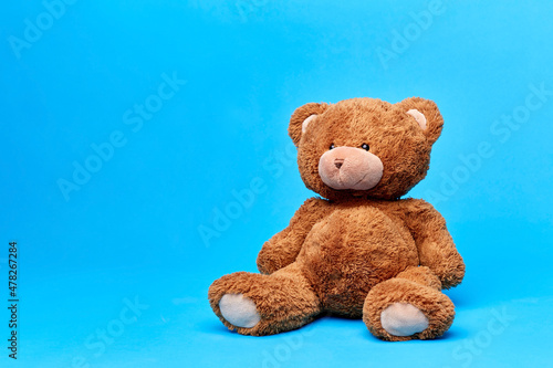soft toys and childhood concept - brown teddy bear over blue background