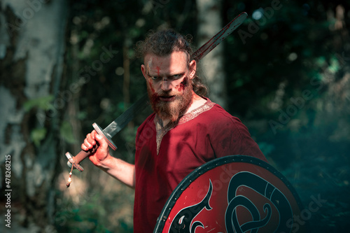 Brave viking showing sharp sword for historic reenactment photo