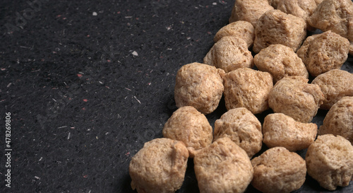 Raw soya chunks on dark background. Healthy, nutritious soybean meat, chunks isolated.Vegan food concept.