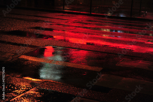 Red neon light reflections on street scene in Paris.  Dark and rainy evening in city. Horizontal photo with copy space. Pedestrian crossing. photo