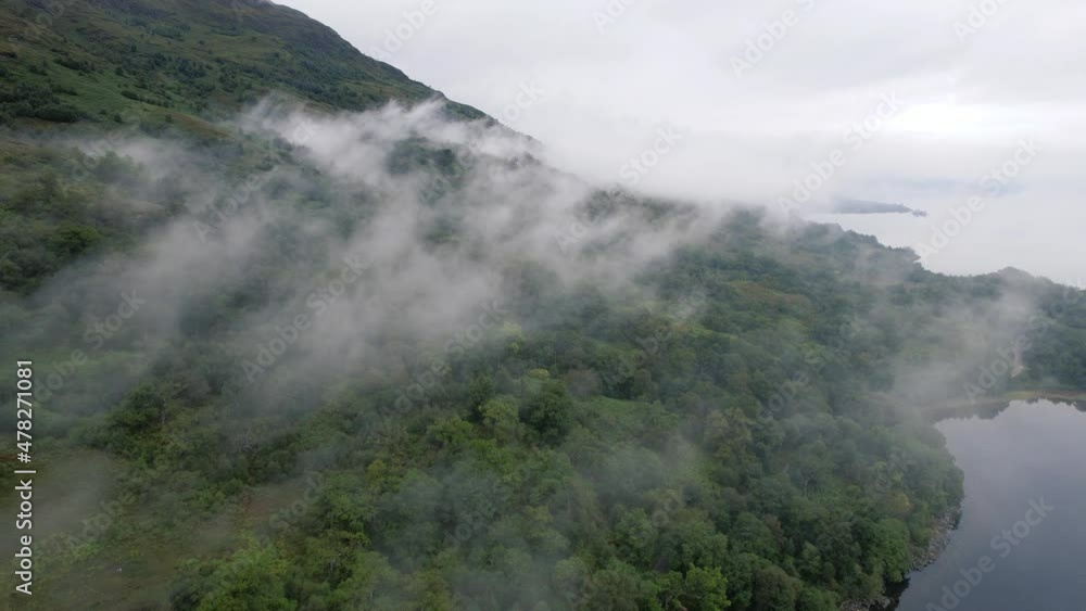 Slow motion cinematic shot of the foggy greens on high mountains near a empty pleasant island in a natural background at Glen Coe, Loch Etive in Scotland Slow motion cinematic shot of the foggy greens on high mountains near a empty pleasant island in a natural background at Glen Coe, Loch Etive in Scotland