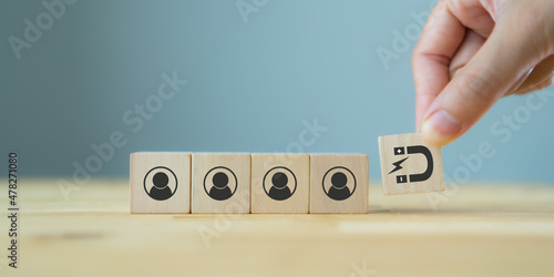 Customer retention concept. Inbound marketing strategy. Attracting potential customers.  Hand puts wooden cubes with magnet attracts customer icons on beautiful grey background and copy space. Loyalty