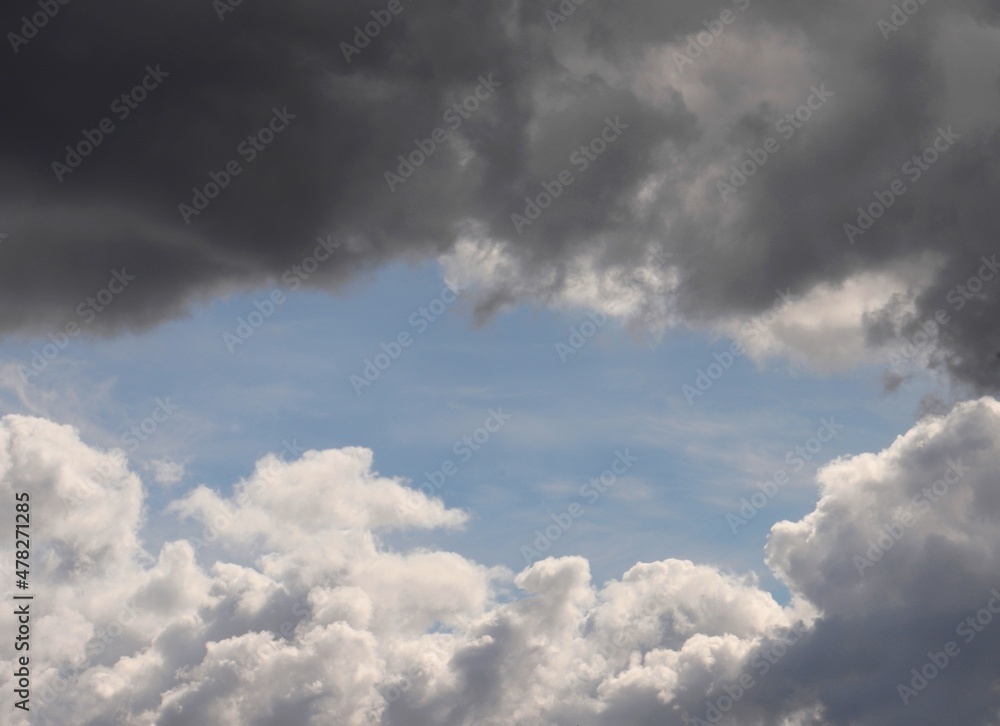 White and dark grey cumulus clouds on blue sky, opposing each other dramatically. Cloudscape background wallpaper showing the concept of polarity.