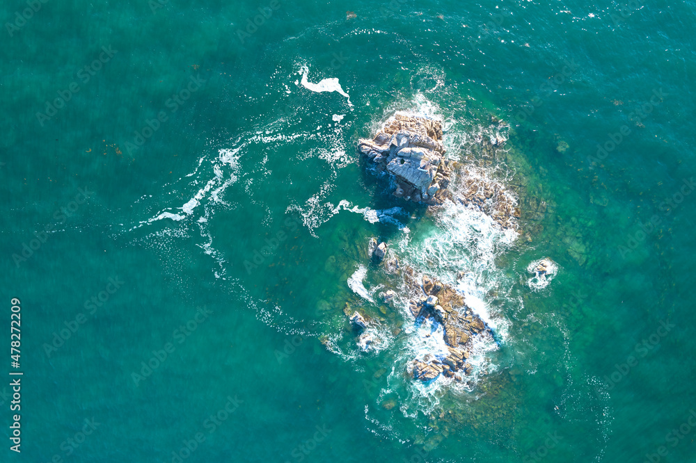 Small island from above. Aerial view of rocks in blue atlantic water.