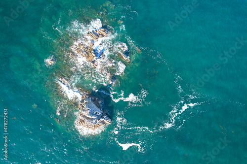Small island from above. Aerial view of rocks in blue atlantic water.