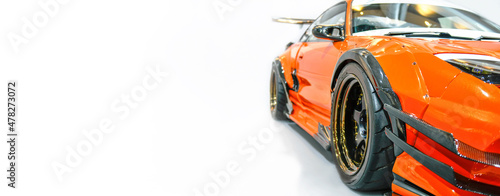 Front headlights of orange modify car on white background, copy space