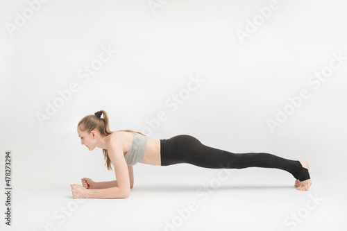 Exercise plank. Young woman doing pilates, working on the abdominal muscles on white background. Girl is engaged. Asana in yoga.