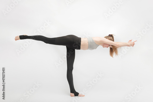 Balancing Stick Pose. Tuladandasana. Side view is portrait of beautiful young woman doing yoga or gymnastics on white background.