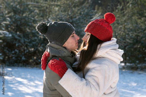 Happy lovers embrance in winter forest. Young couple walking outside. Declaration of love