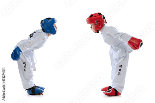 Two little kids, boys, taekwondo athletes training together isolated over white studio background. Concept of sport, education, skills