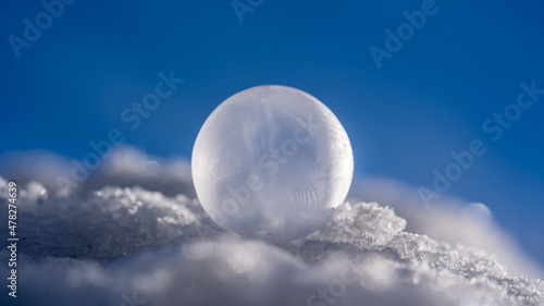 frozen soap bubble on snow at a cold clear winter morning