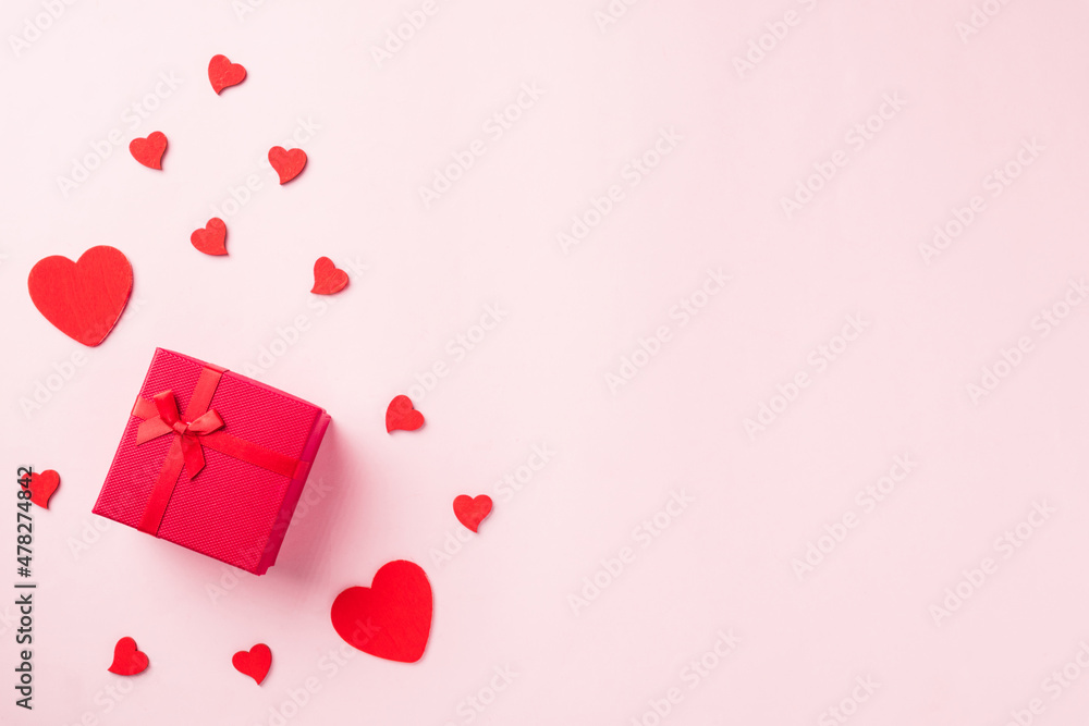 Valentines' day background. Red gift box with ribbon bow and wood red hearts shaped composition greeting card for love isolated on pink background with copy space. Top View from above Valentines' day background. Red gift box with ribbon bow and wood red hearts shaped composition greeting card for love isolated on pink background with copy space. Top View from above