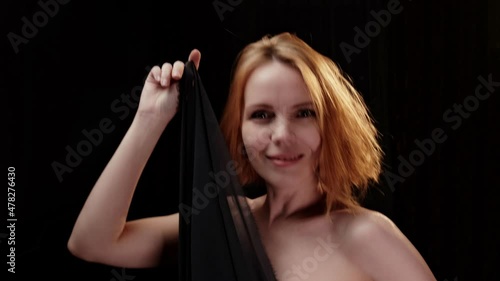 Seductive forty-year-old woman. Movement with a cloth in the dark. Pleasure, happy face.