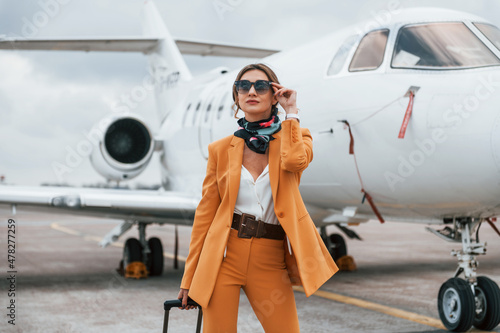 Cloudy weather. Passenger woman that is in yellow clothes, sunglasses and with luggage