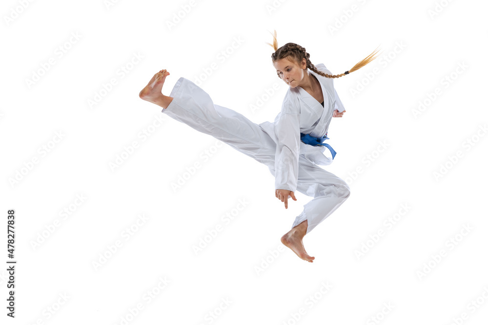 Dynamic portrait of young girl, teen, taekwondo athlete jumping isolated over white background. Concept of sport, education, skills Dynamic portrait of young girl, teen, taekwondo athlete jumping isolated over white background. Concept of sport, education, skills