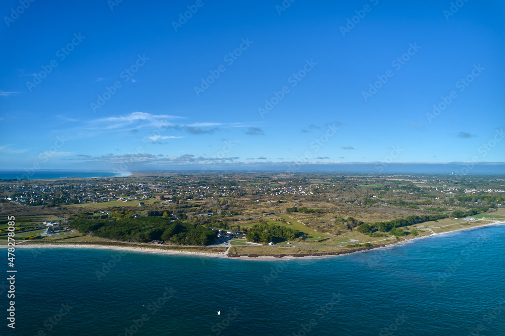 Aerial view of a french city on the atlantic ocean. Water edge on the beach. Blue sky for copy space. France, Brittany, Penmarch.
